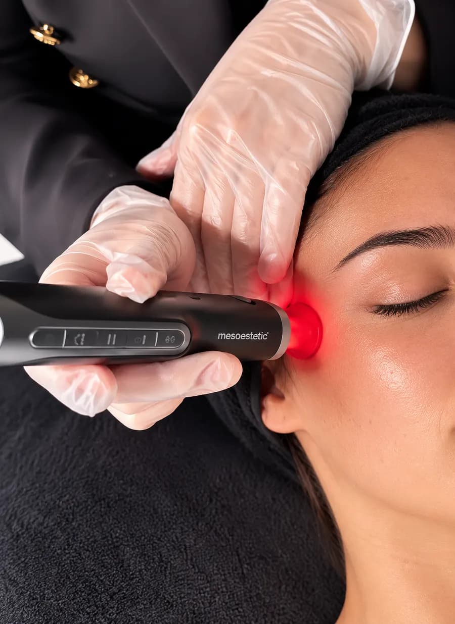 Soin Mesoestetic appliqué au contour de l'œil par une professionnelle gantée, avec un appareil de la marque, en cabine Luxury Glow.